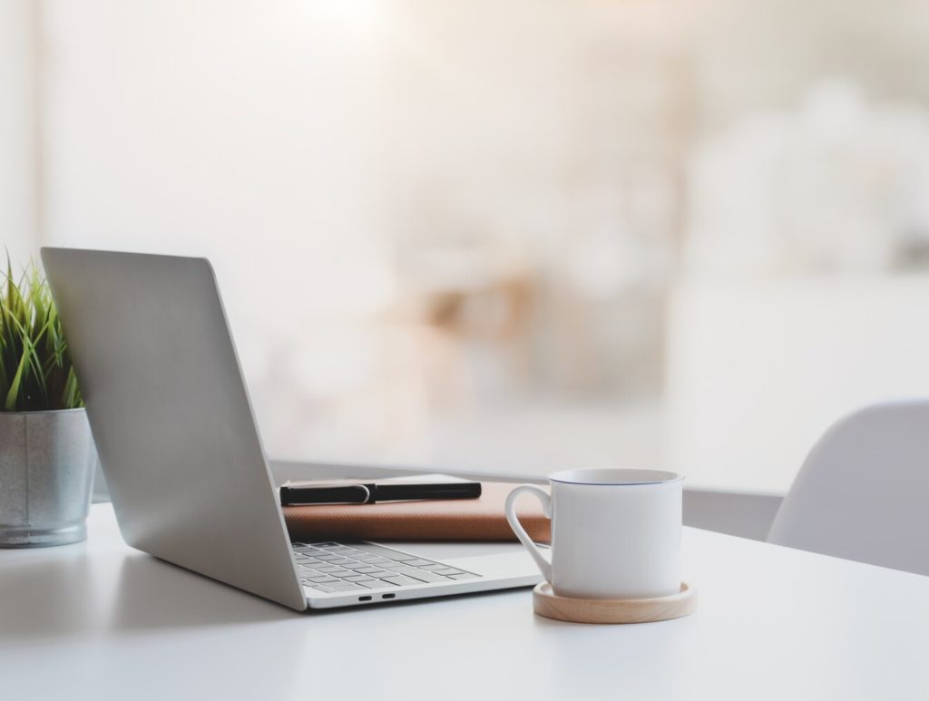 Modern workplace with laptop computer, coffee cup and office supplies
